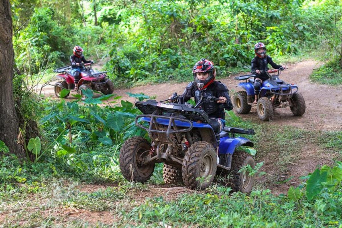 tre persone che guidano quad su una strada sterrata
