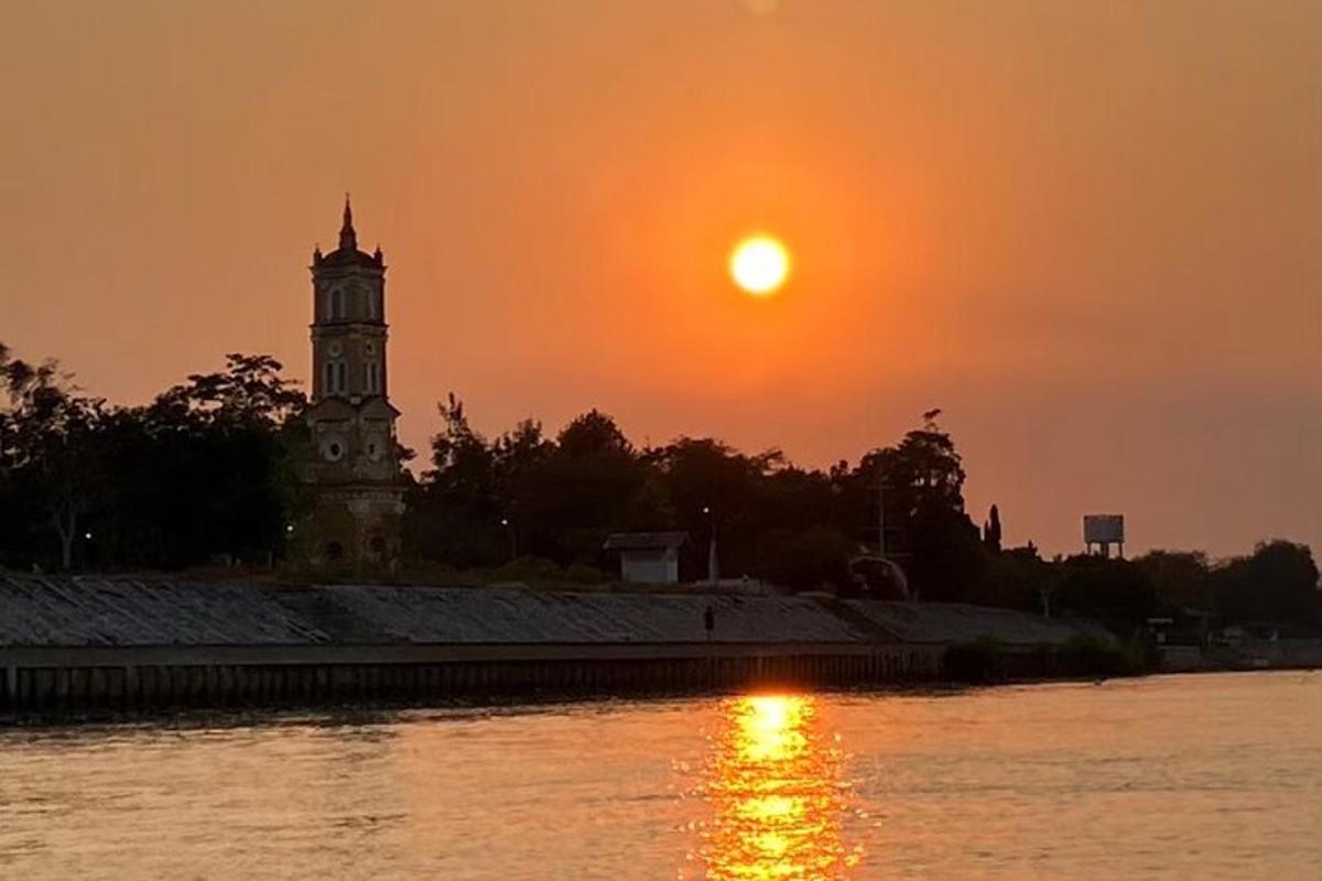 un tramonto su un fiume con una torre dell'orologio