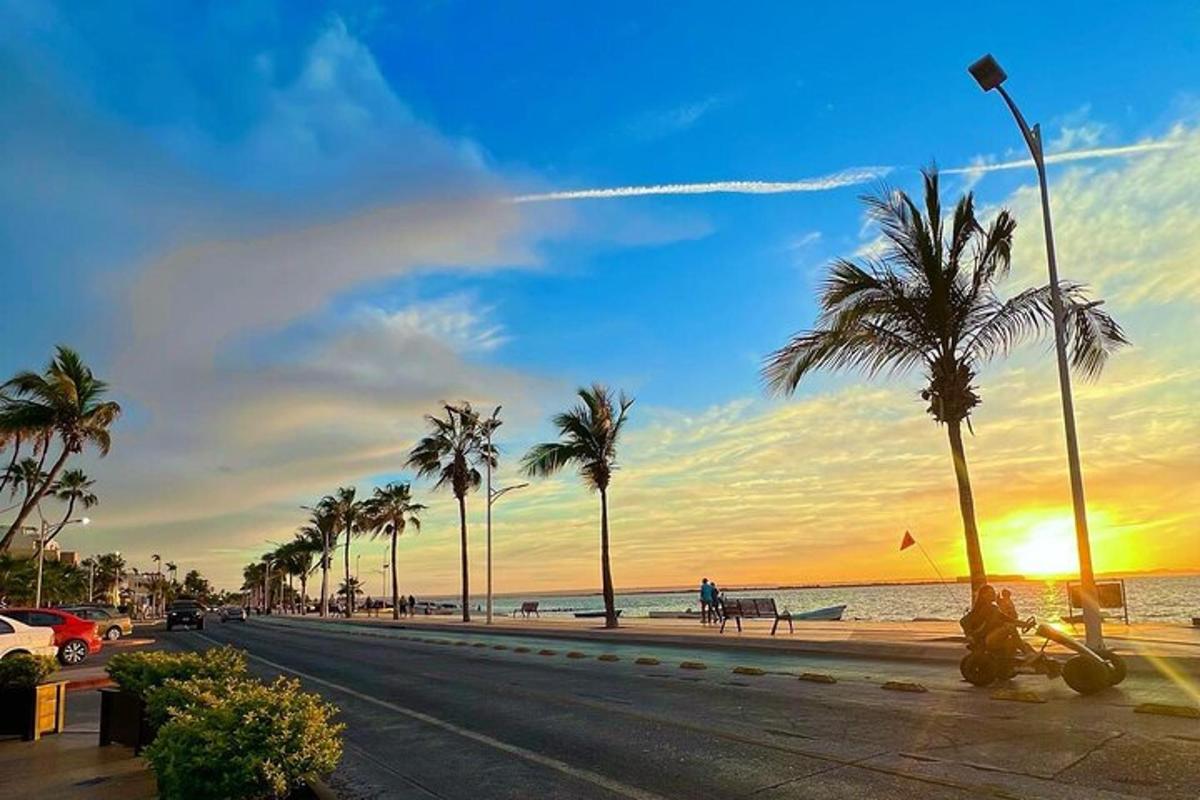 una strada con palme e l'oceano al tramonto
