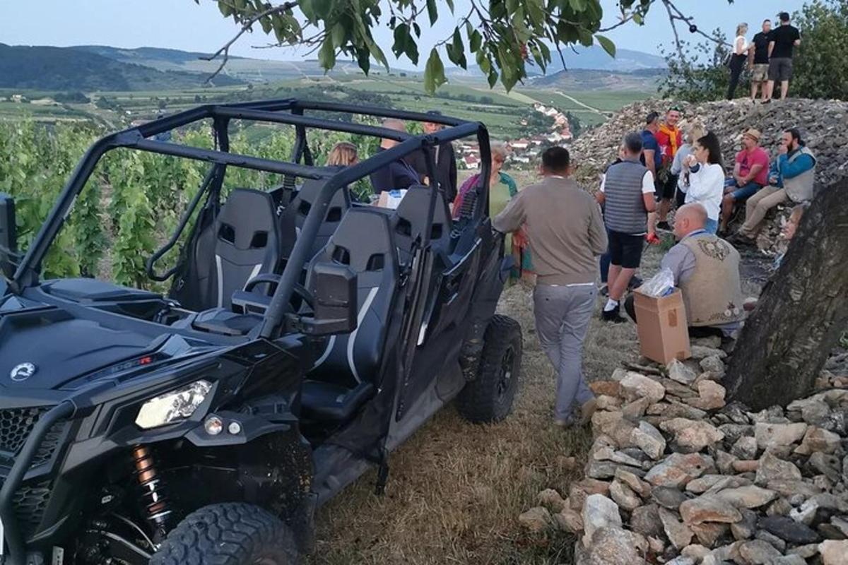 a group of people standing around a jeep on a hill