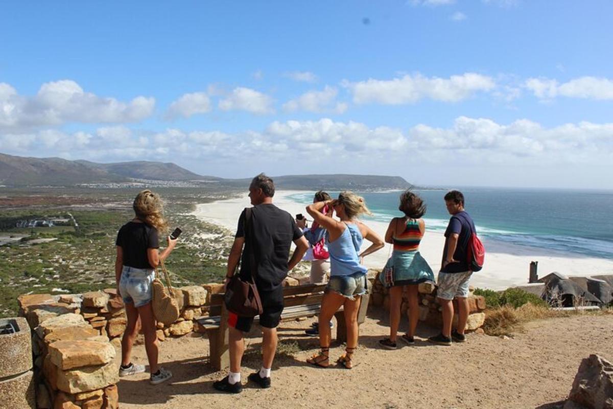 a group of people standing on a wall looking at the beach