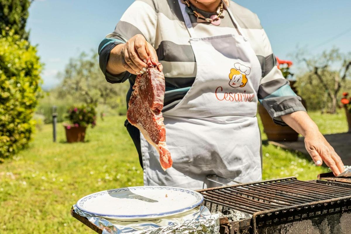 uma mulher cozinhando um pedaço de carne na grelha