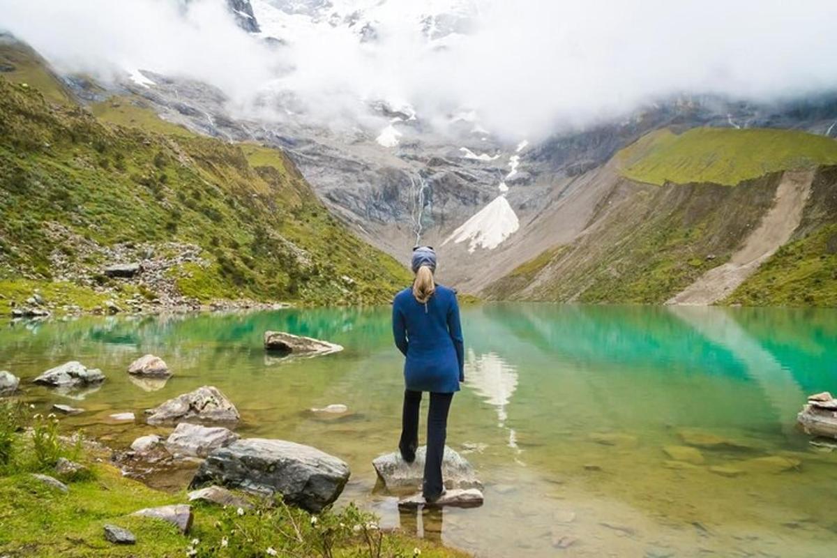 Una mujer parada sobre una roca en un lago de montaña