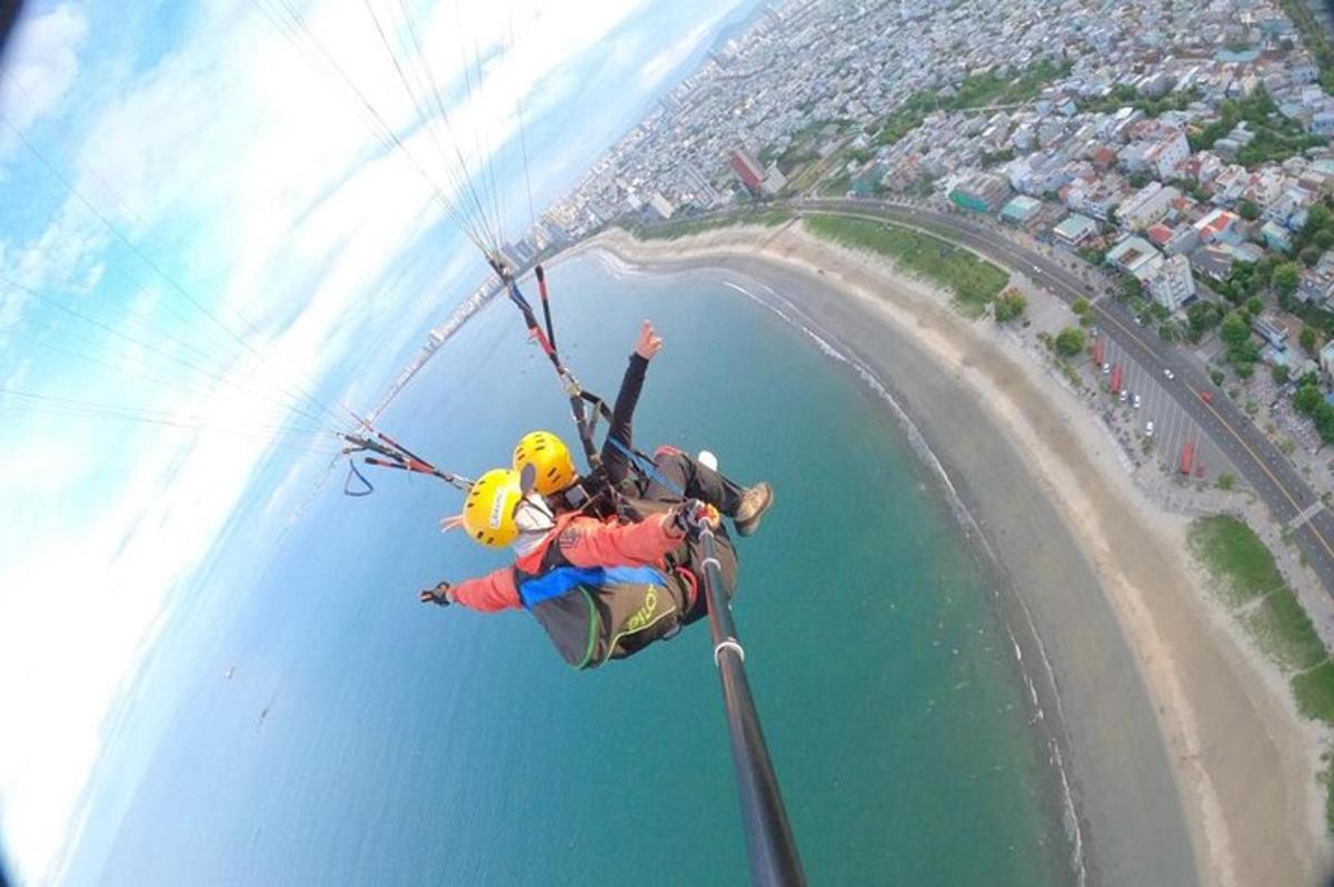 een man die door de lucht vliegt terwijl hij met een parachute over het water rijdt