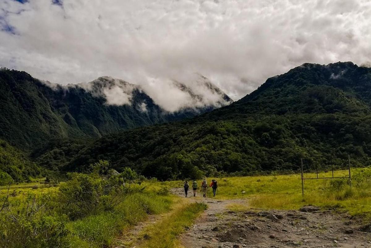 a group of people walking down a dirt road through a mountain