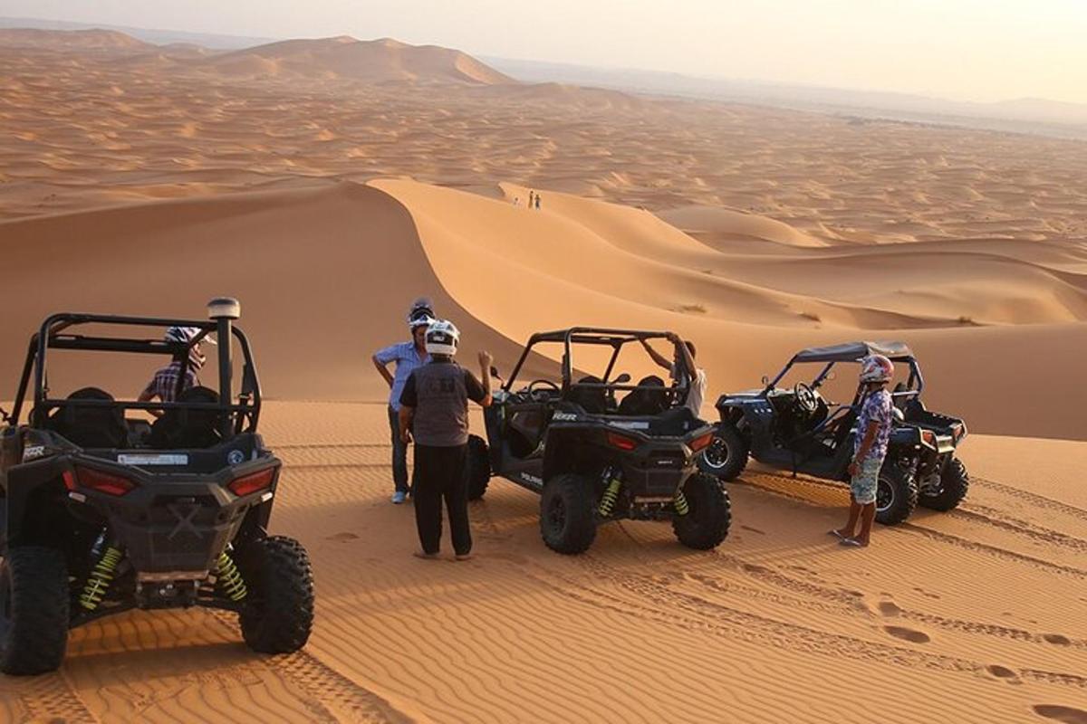 um grupo de pessoas em pé no deserto com quadriciclos