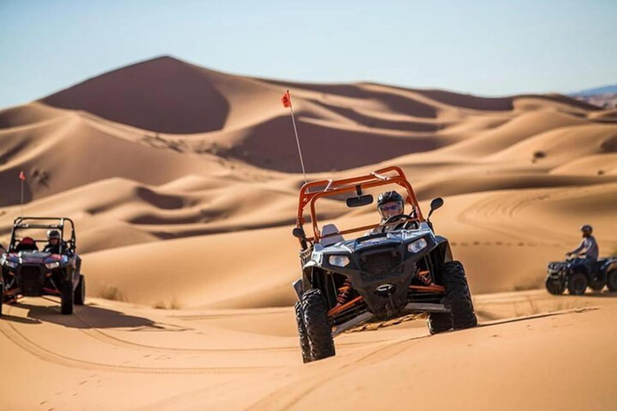 duas pessoas em quadriciclos na areia do deserto