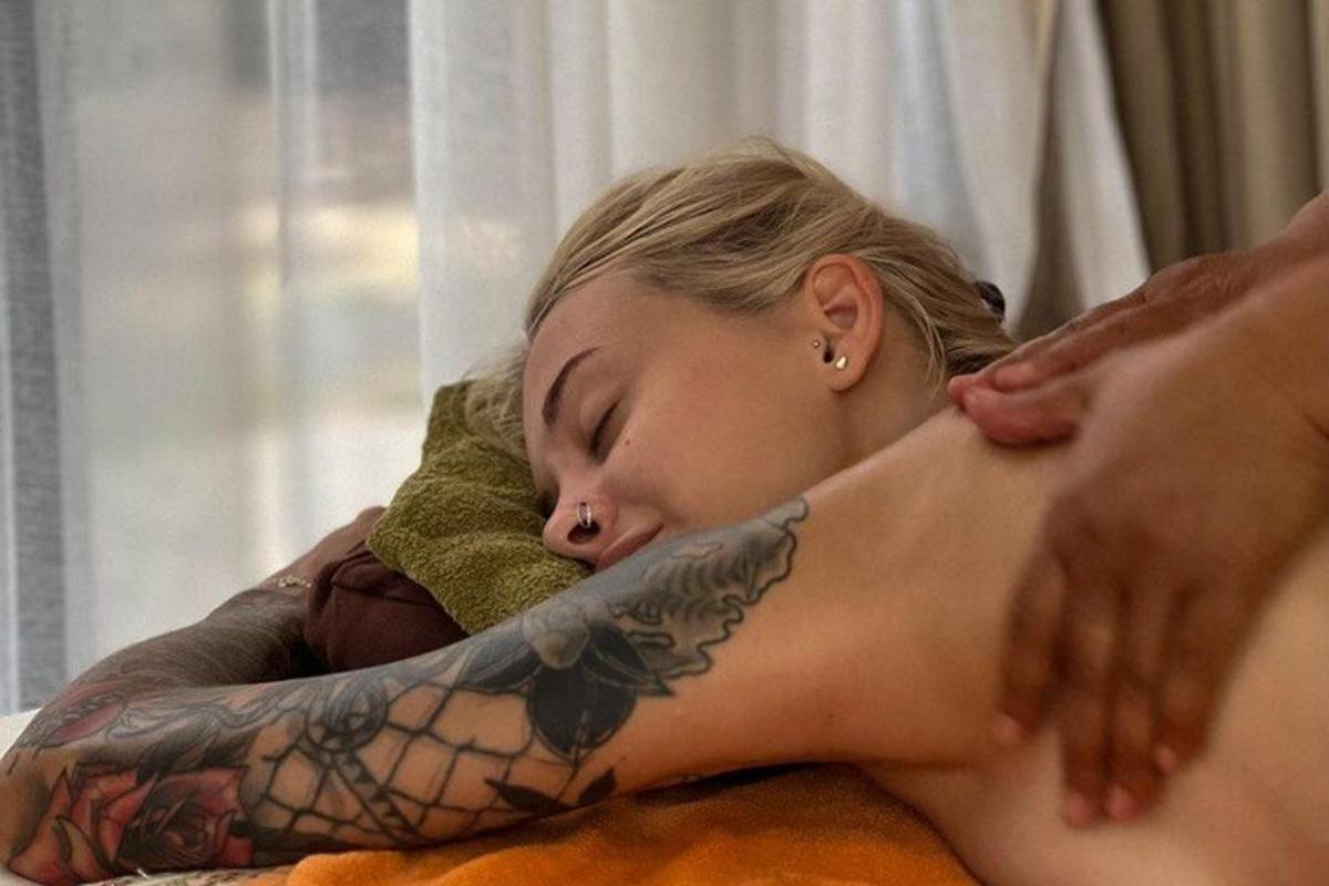 una donna sdraiata su un letto con un tatuaggio sul braccio