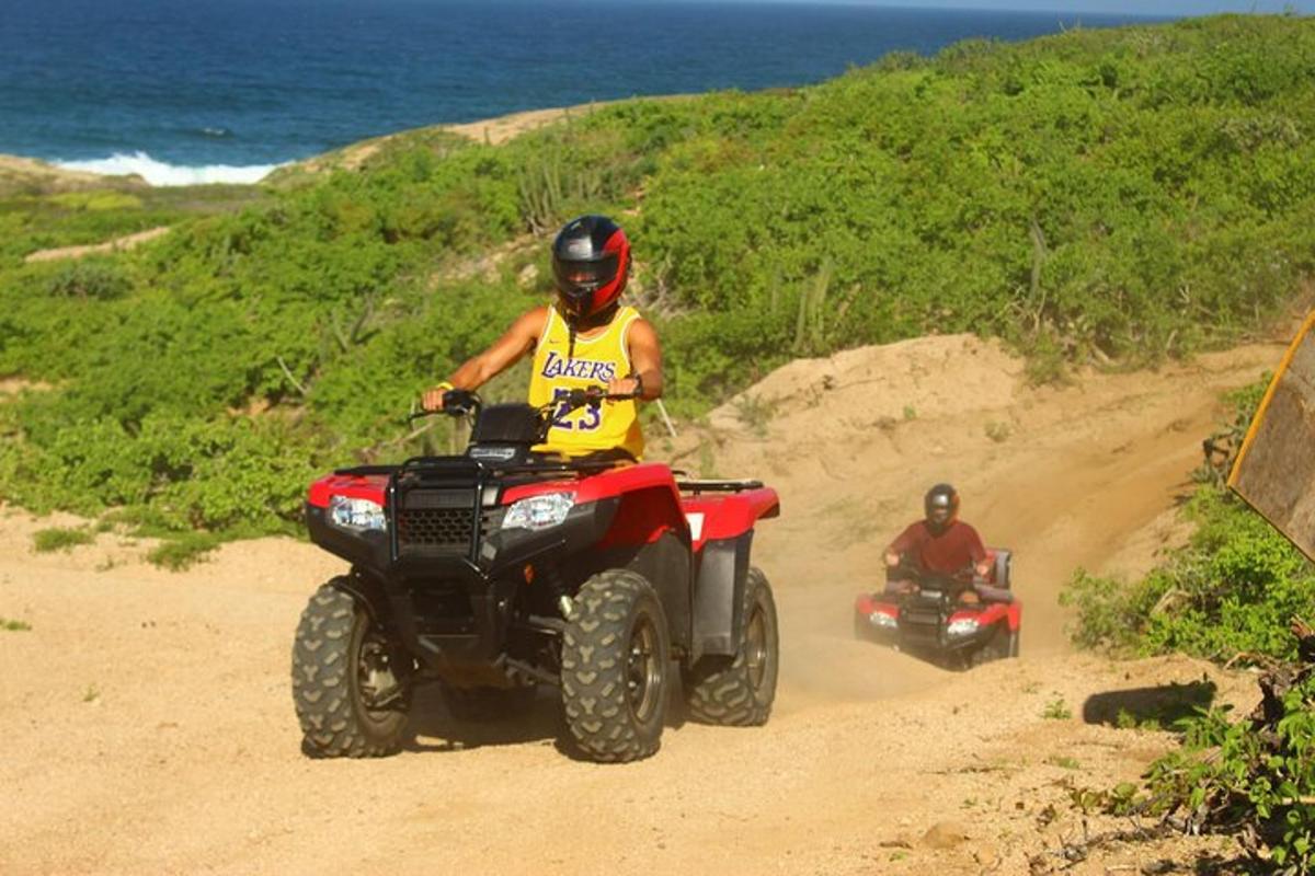 due persone che guidano un quad su una strada sterrata