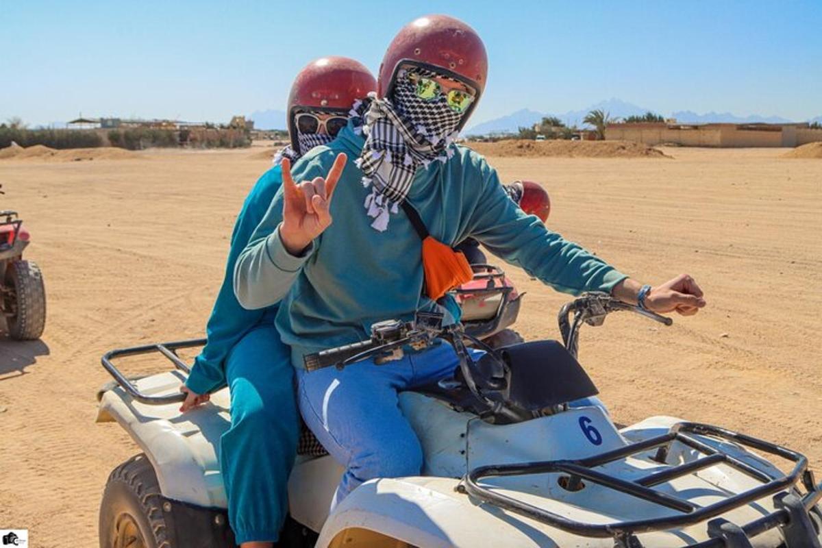 dua orang menaiki basikal quad di padang pasir