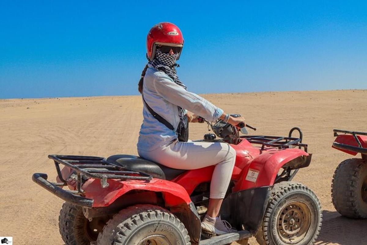 seorang wanita menunggang basikal quad di padang pasir
