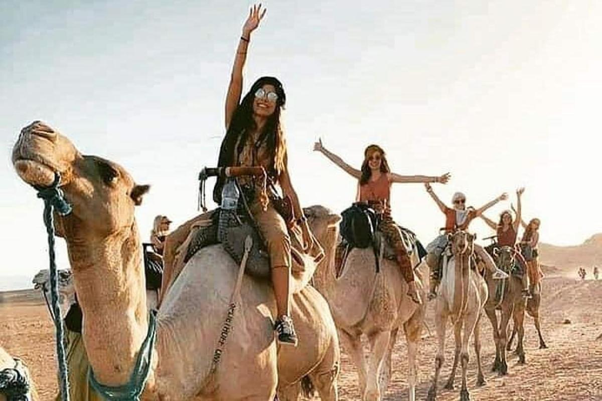 skupina lidí jedoucích na velbloudech v poušti