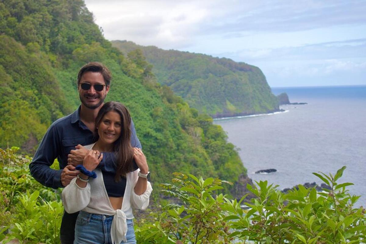 a man and a woman standing on a hill near the ocean