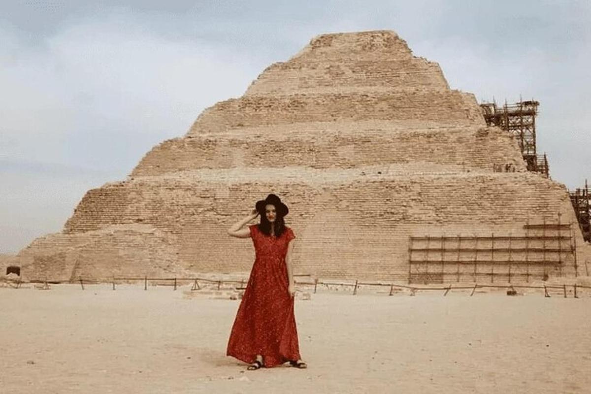 žena v červených šatech stojící před pyramidou