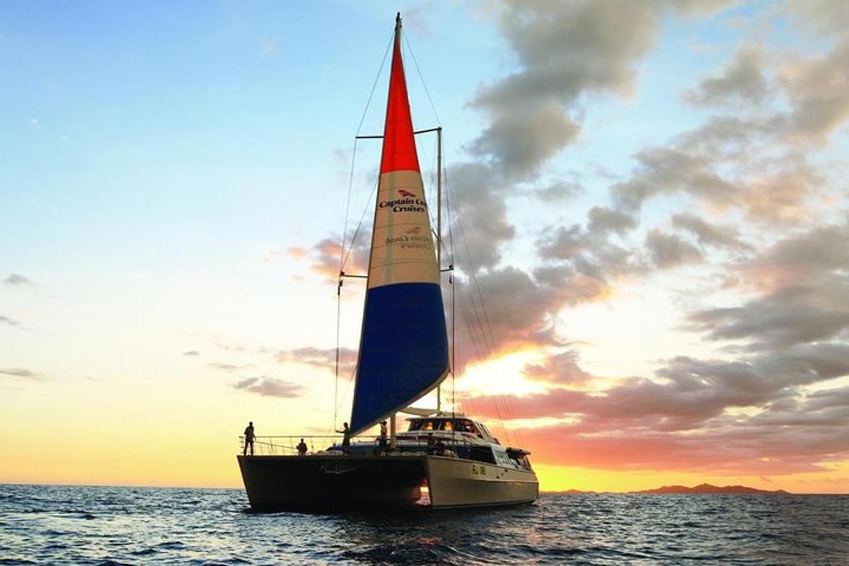 a sail boat in the water with a sunset
