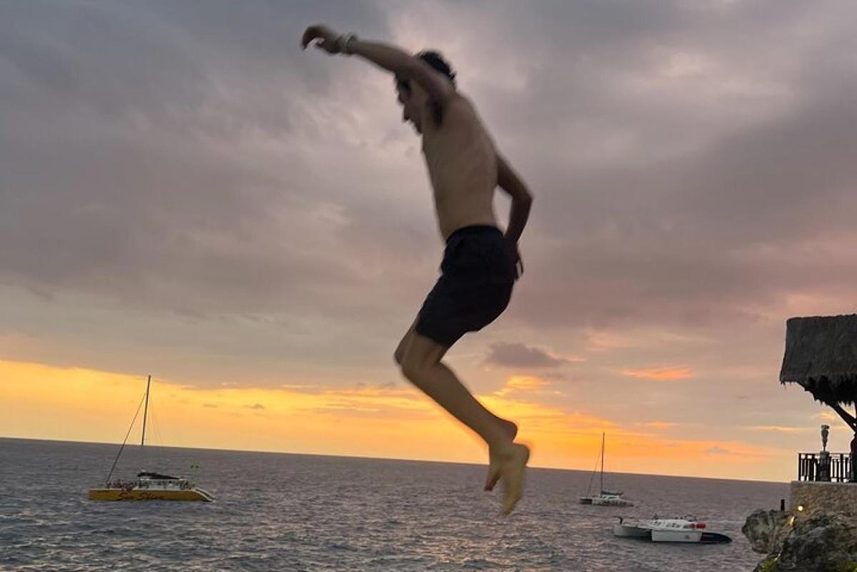 un uomo che salta in aria di fronte all'oceano