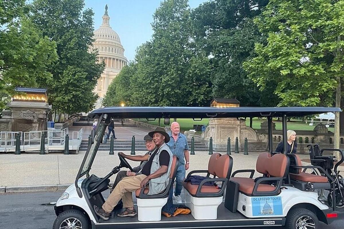 Un grupo de personas en un carrito de golf frente al edificio del Capitolio.