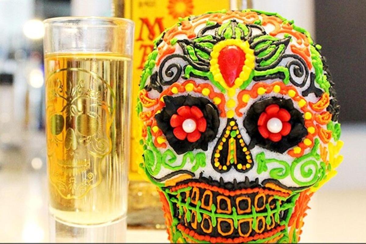 a sugar skull vase next to a glass of beer