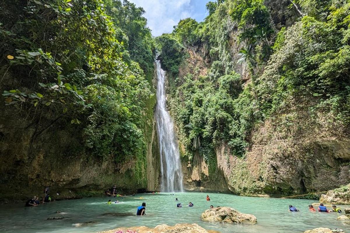 a group of people swimming in a pool in front of a waterfall