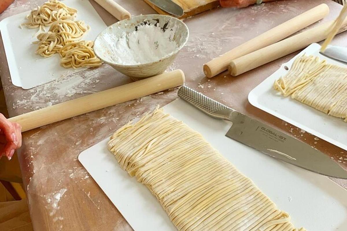 Una mesa con pasta cruda y un cuchillo sobre una tabla de cortar