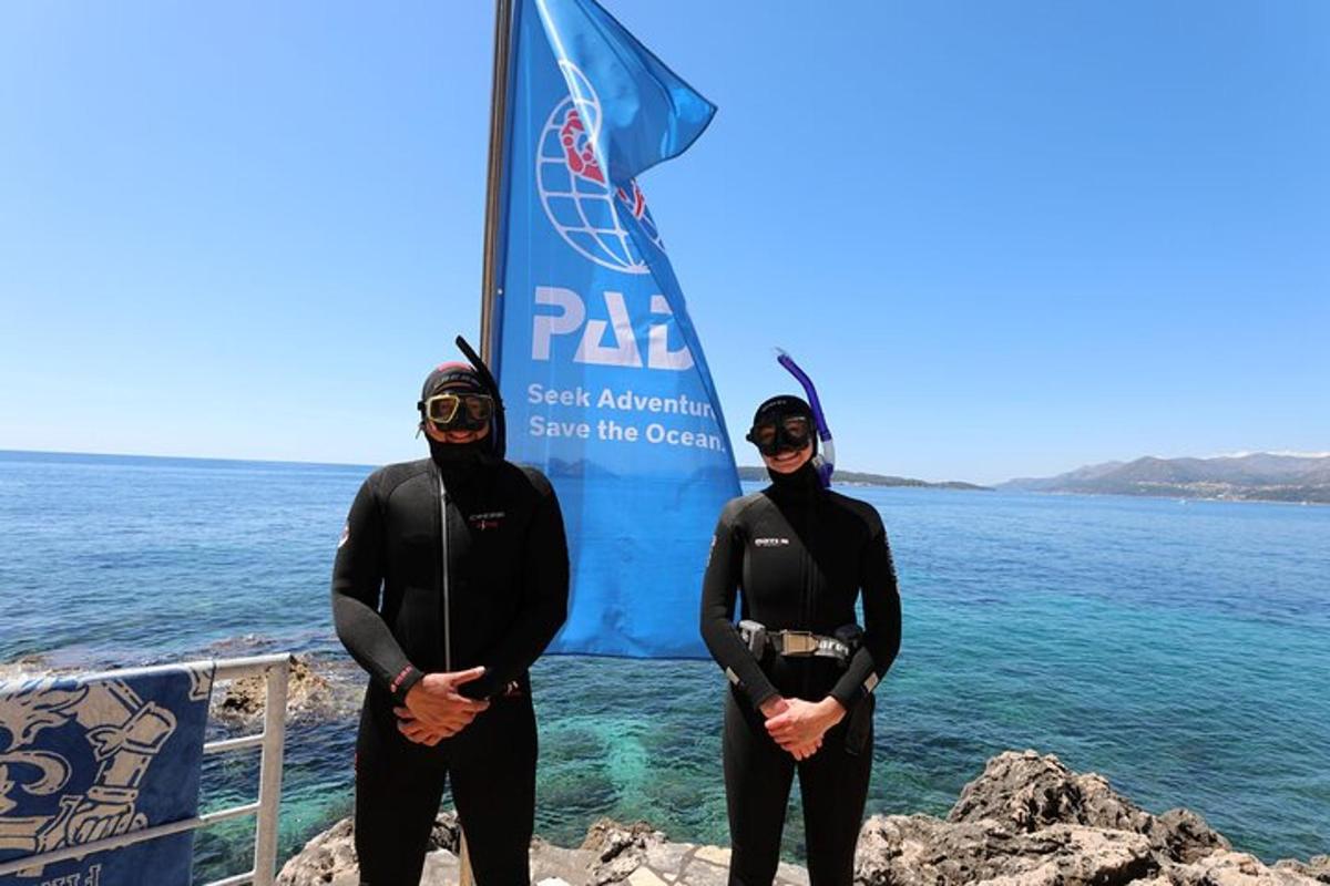 due persone in muta in piedi di fronte all'oceano