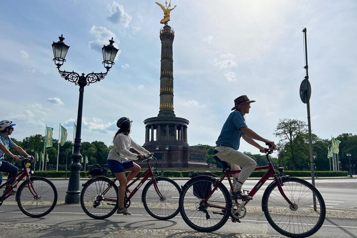 skupina lidí jedoucích na kolech před památníkem
