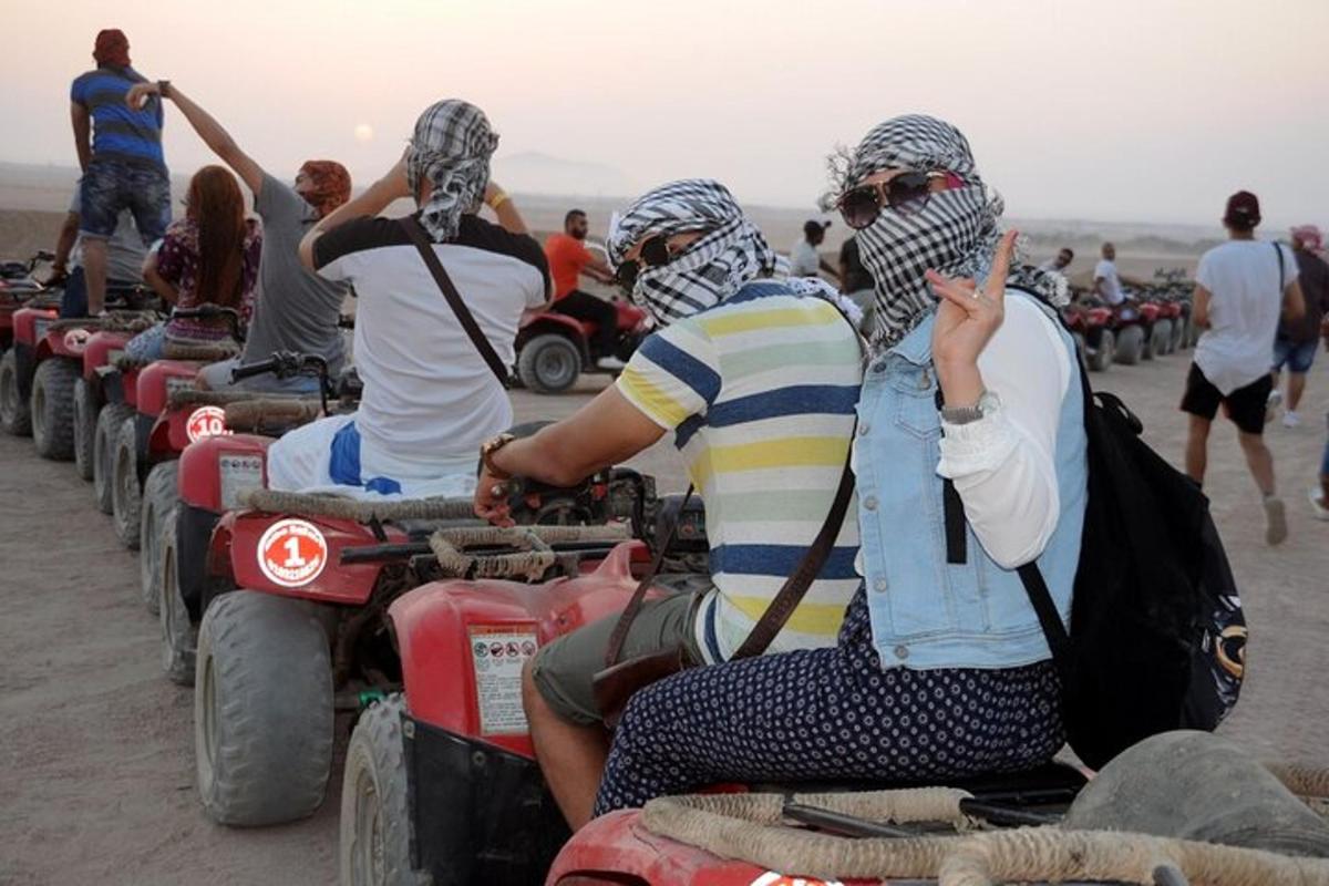sekumpulan orang menunggang basikal quad di padang pasir