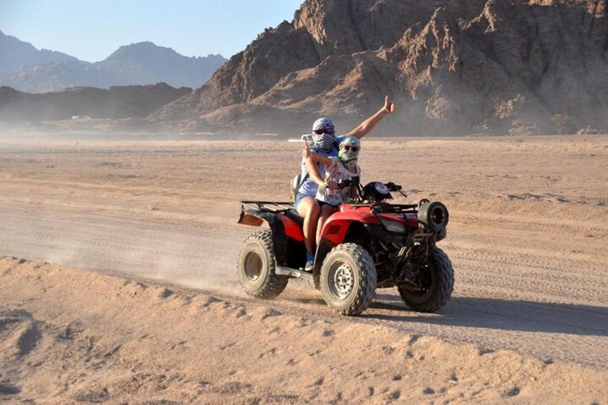 dua orang menunggang basikal quad di padang pasir