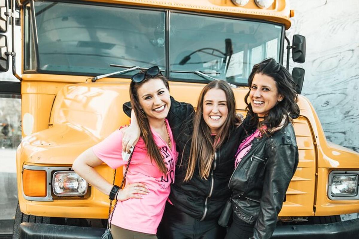 three girls standing in front of a school bus