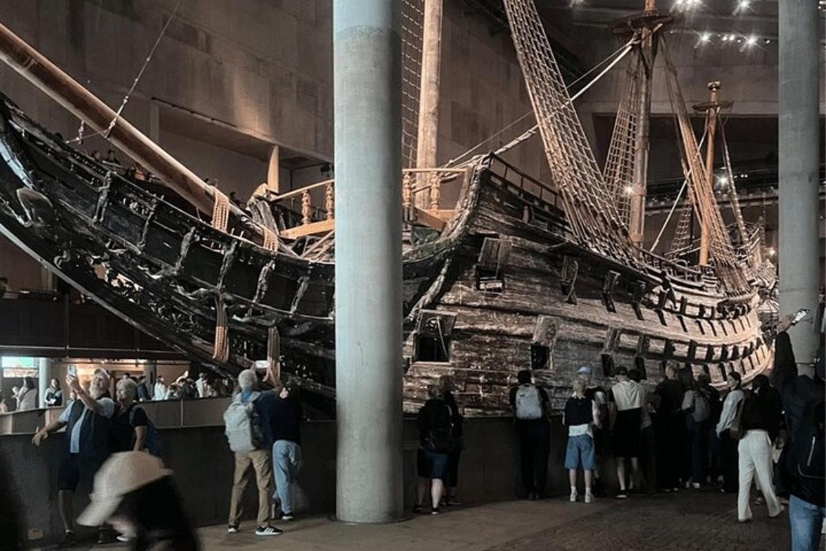 a group of people standing around a museum with a ship