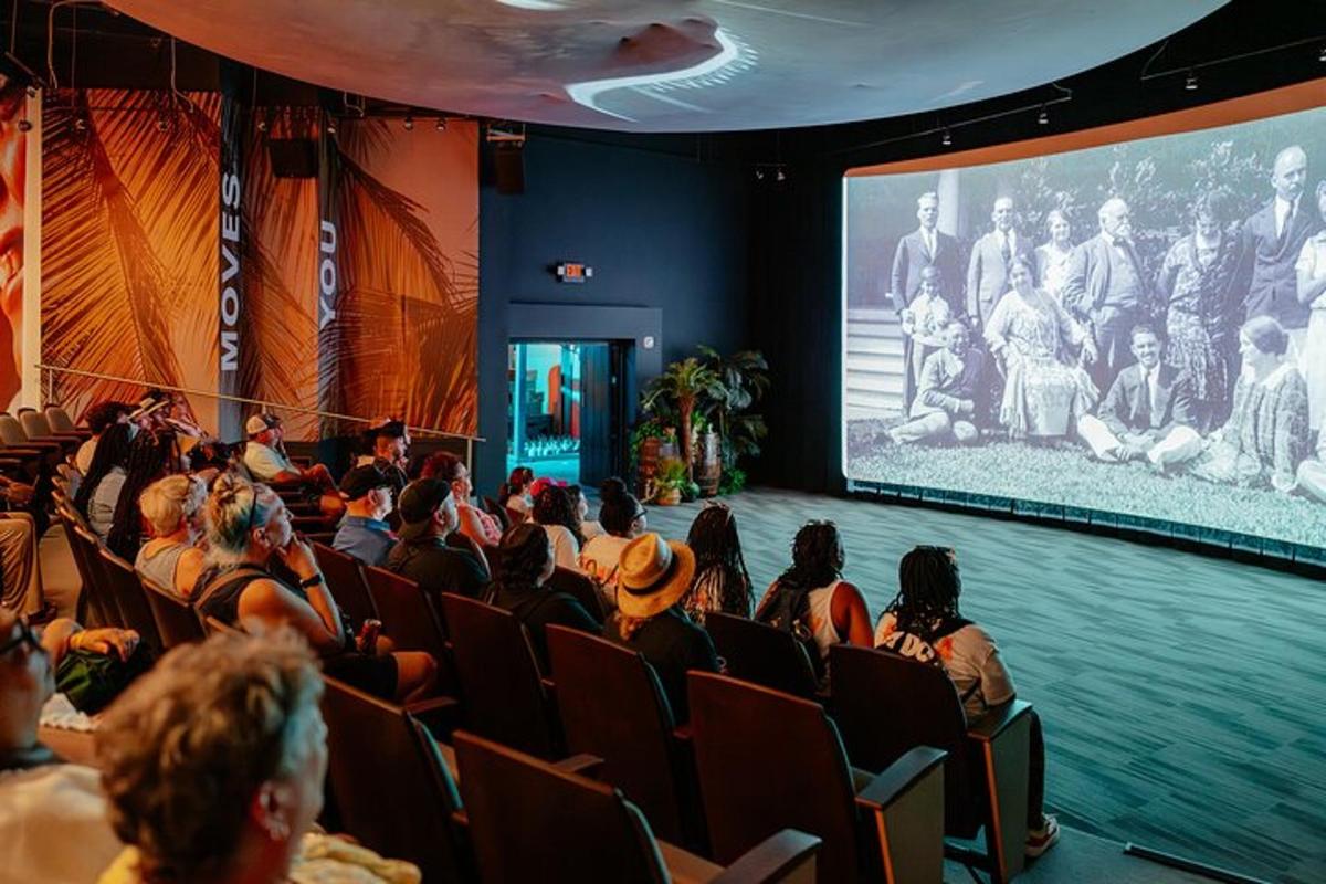 a crowd of people sitting in a theater watching a screen