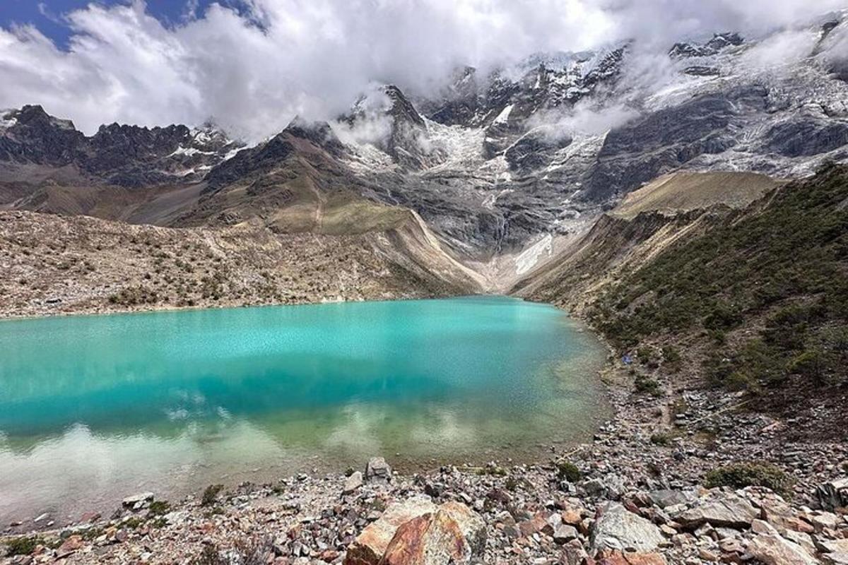 ein blauer See auf einem Berg mit schneebedeckten Bergen