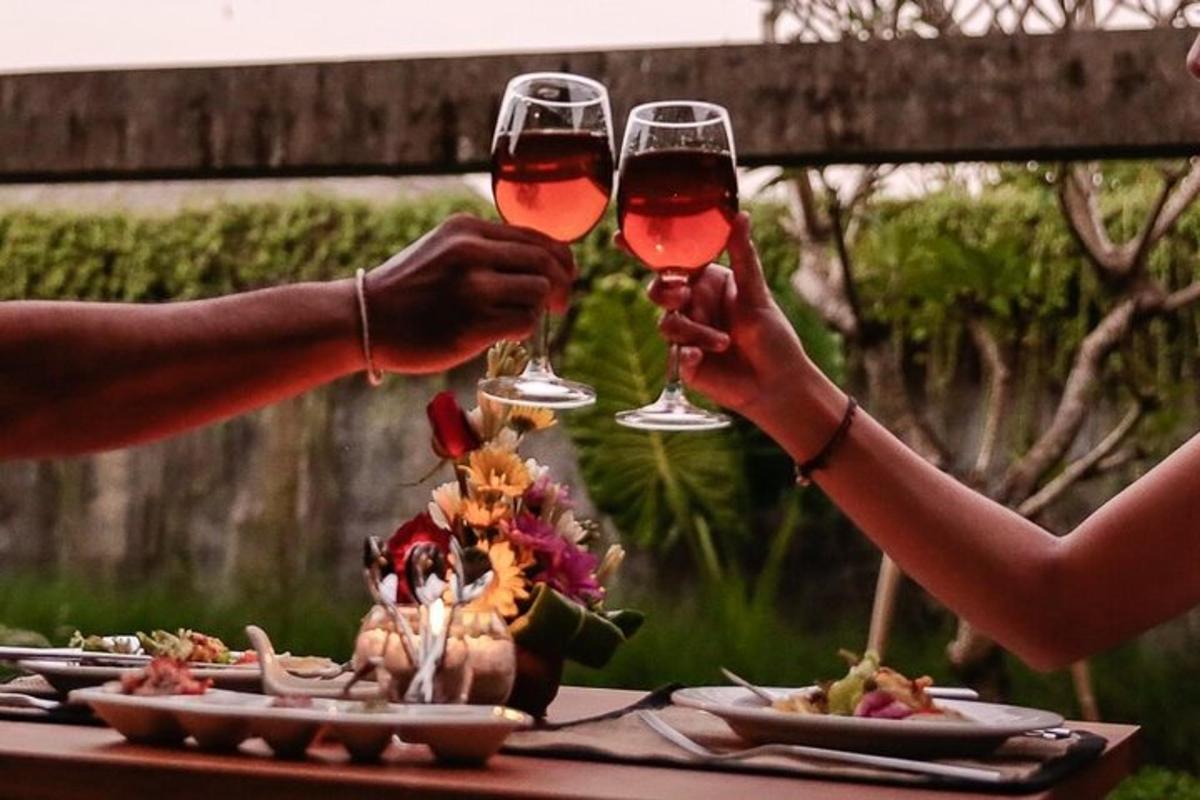 due persone che tengono in mano dei bicchieri di vino a un tavolo