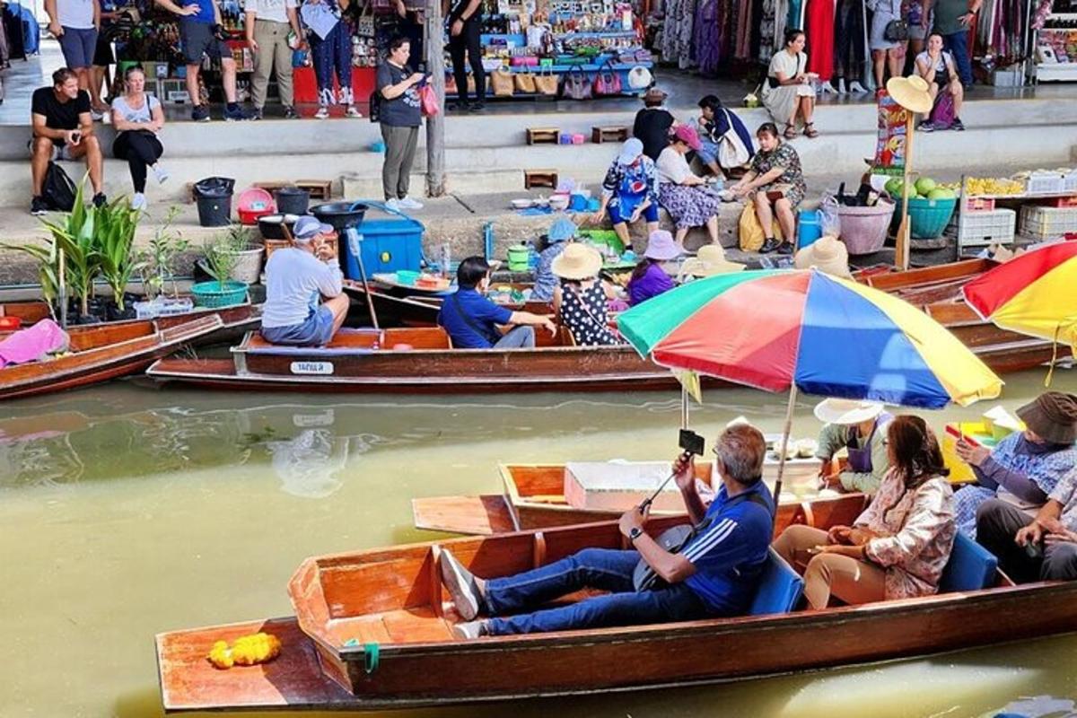un gruppo di persone sedute su barche in acqua con gli ombrelli