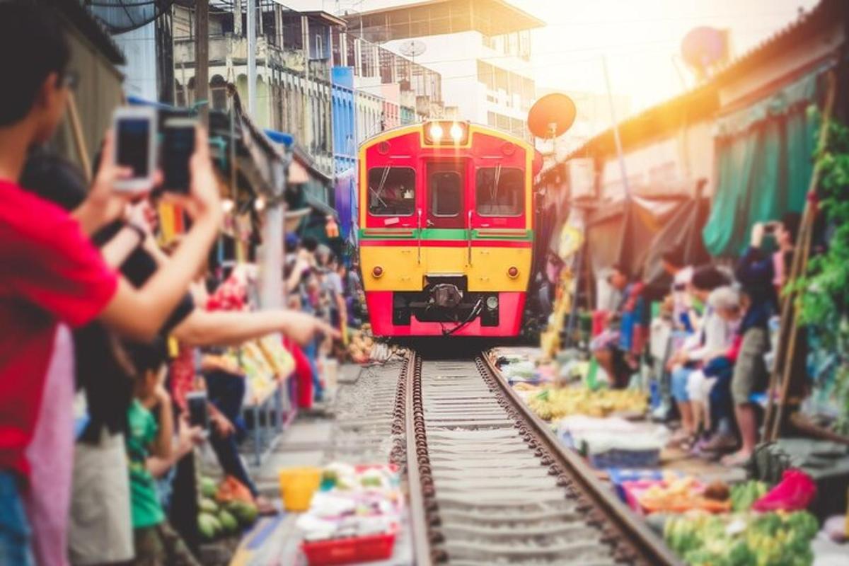 a red and yellow train on tracks with people taking pictures