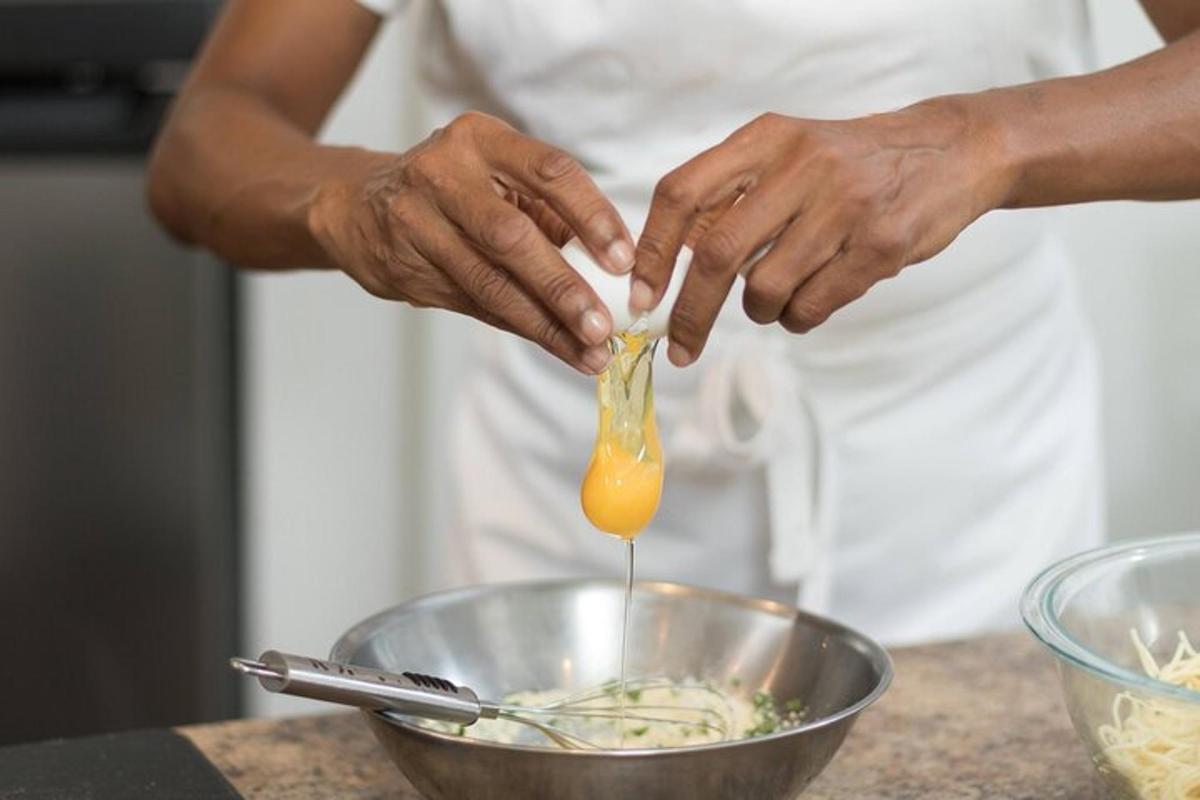 a person adding an egg to a bowl of food