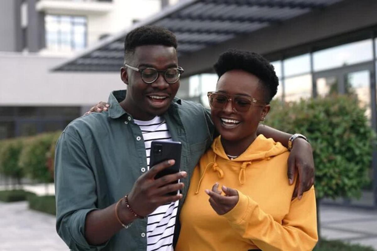 two men are smiling while looking at a cell phone