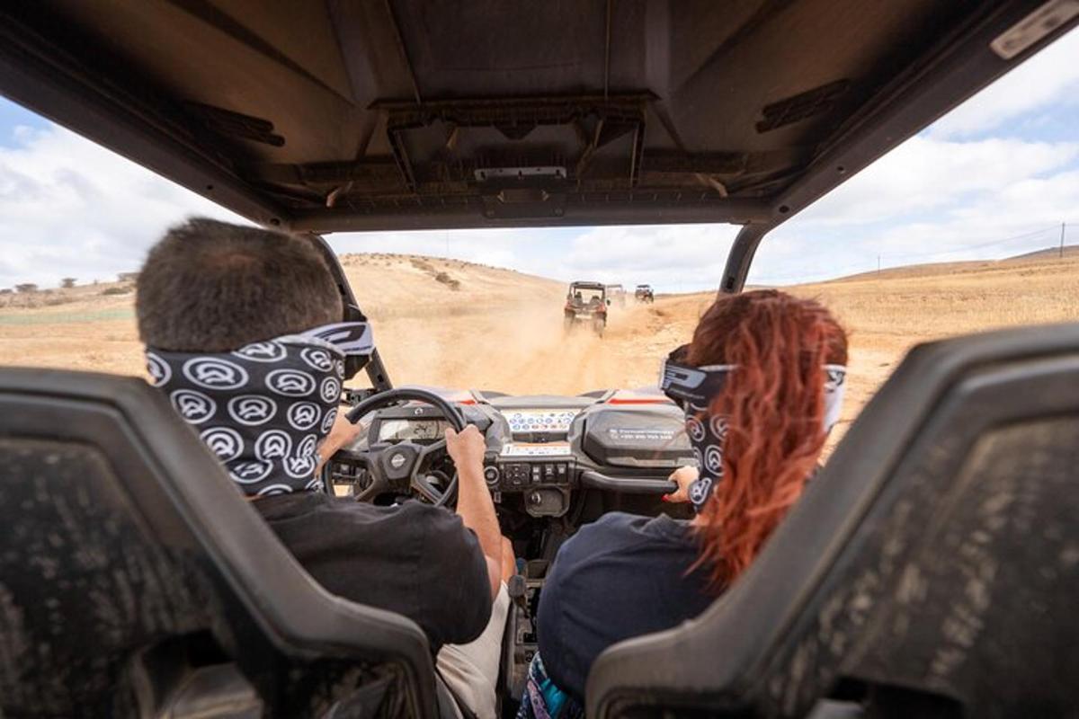 a man and a woman driving a jeep on a dirt road