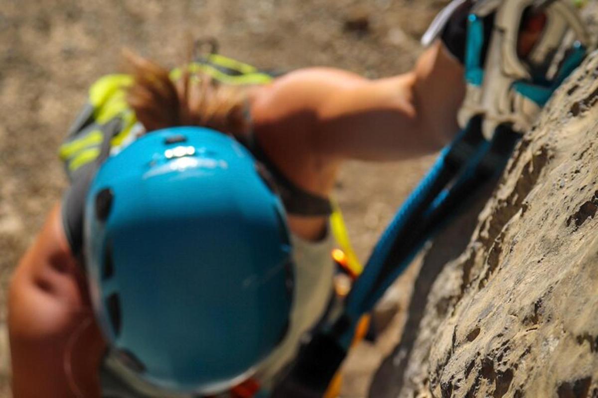 una noia jove està escalant una paret de roca