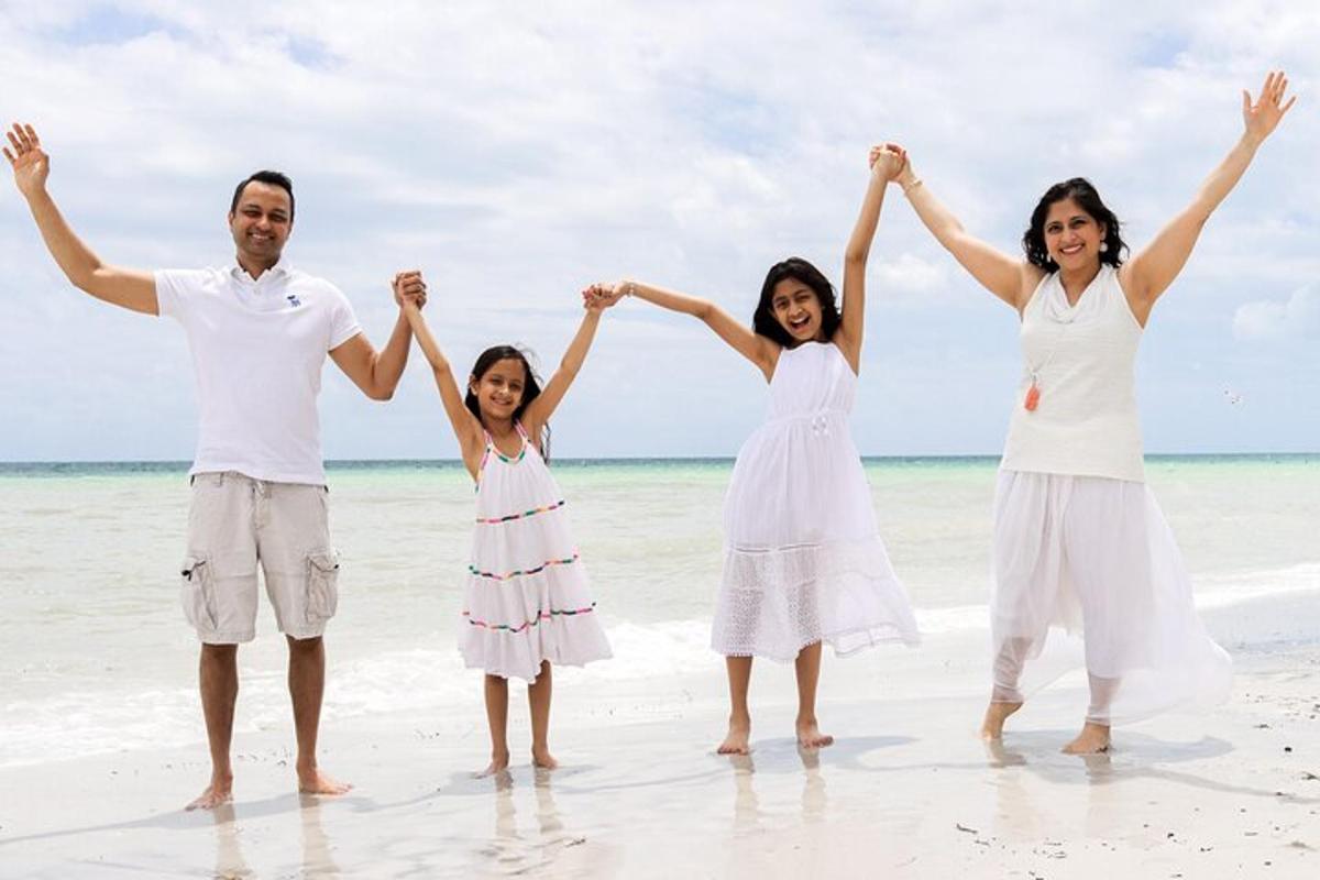 Una familia parada en la playa con las manos en el aire
