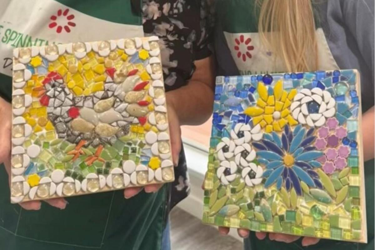 two women holding up mosaicked art in their hands