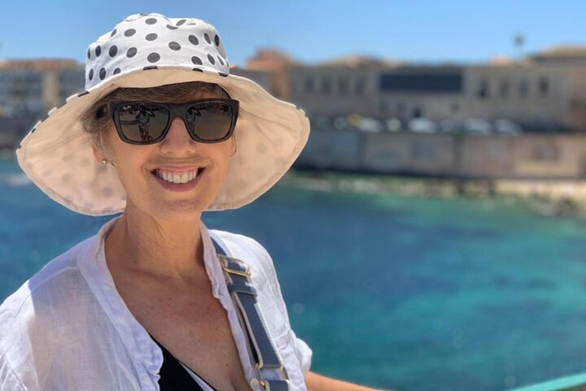 una donna che indossa un cappello e occhiali da sole accanto all'acqua