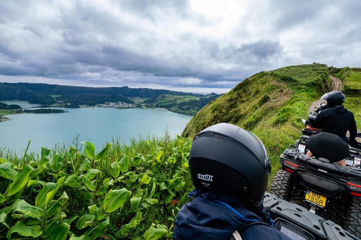 a group of people riding motorcycles on a hill overlooking a lake