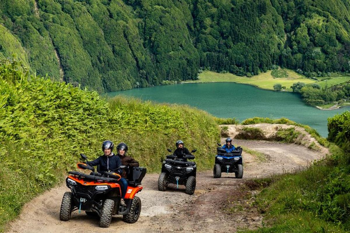 three people on atvs driving down a dirt road