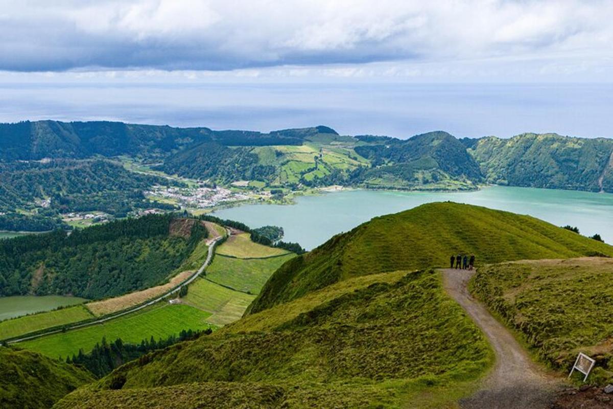 a group of people standing on a hill overlooking a lake
