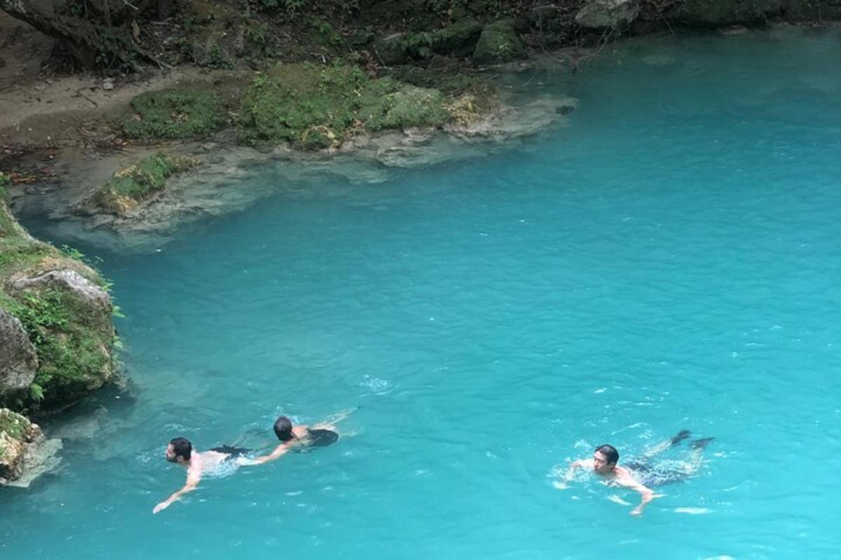 tres personas nadando en una piscina de agua azul