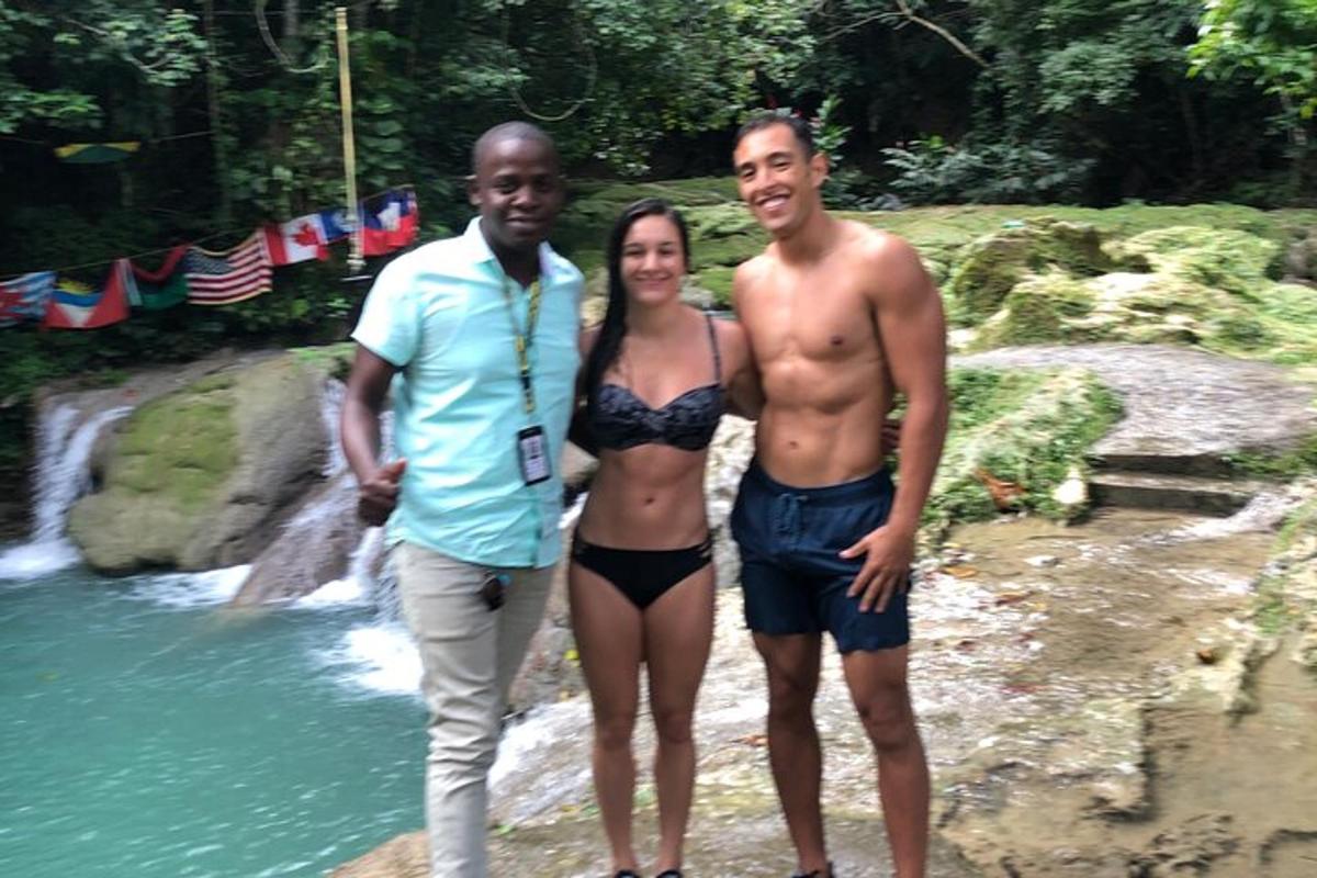 Dos hombres y una mujer de pie junto a un río