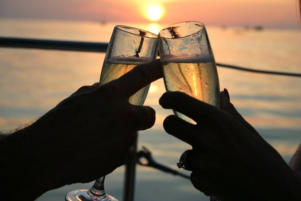 due persone che tengono in mano bicchieri di champagne di fronte all'oceano