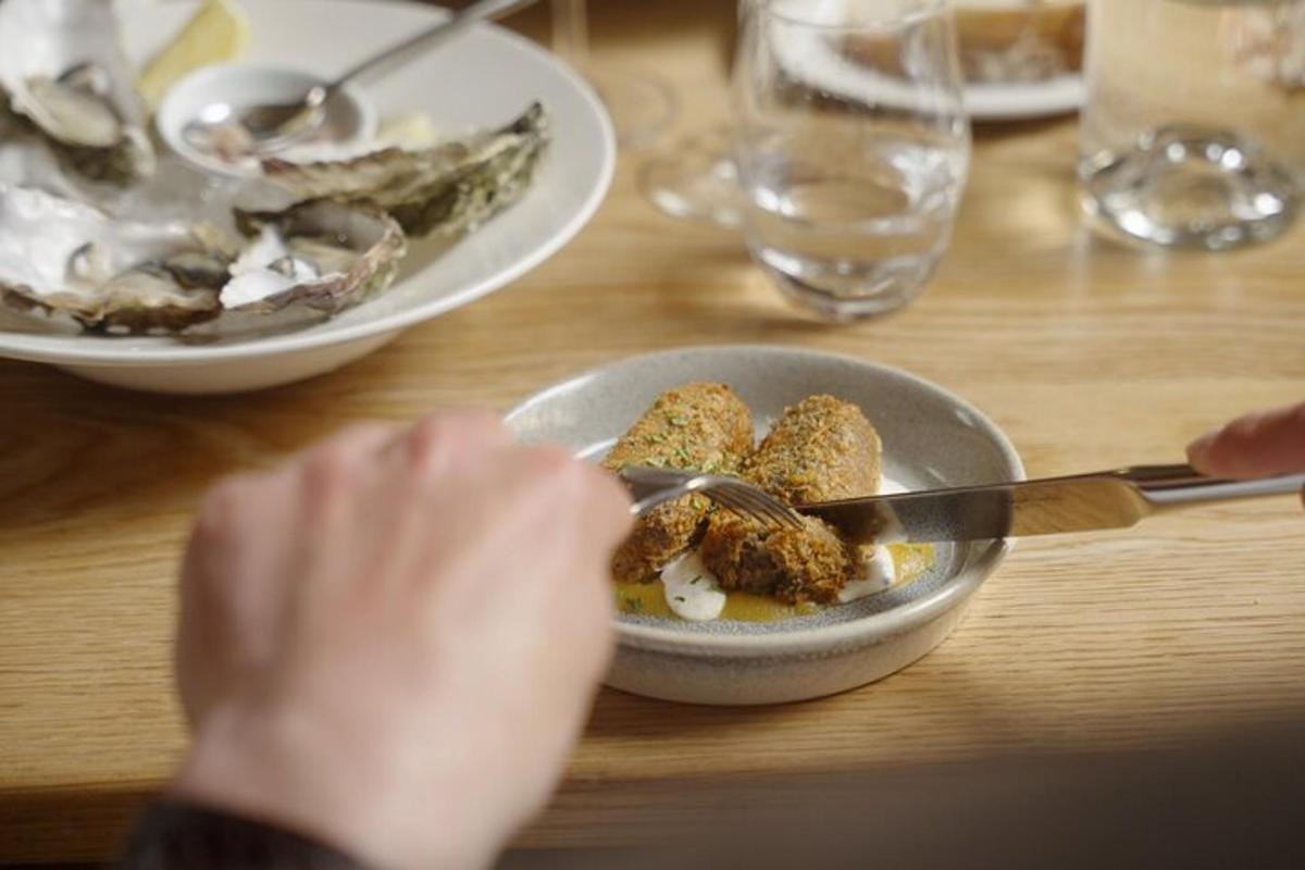 borð með skál af mat og diskum af ostrur