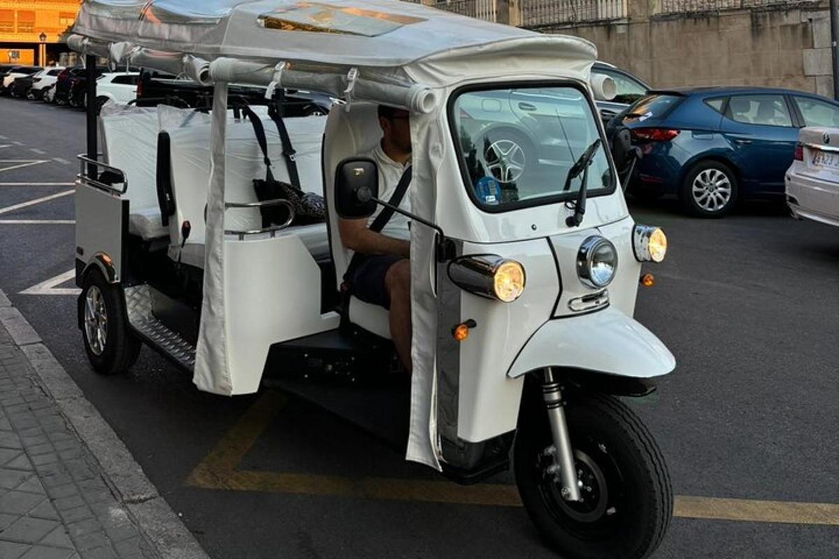 malý biely golfový vozík, v ktorom sedí muž